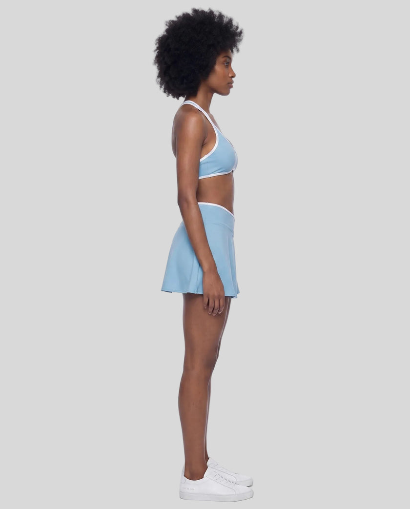 Side view of a model wearing the CourtClub Color Block A-Line Skirt in Sky Blue