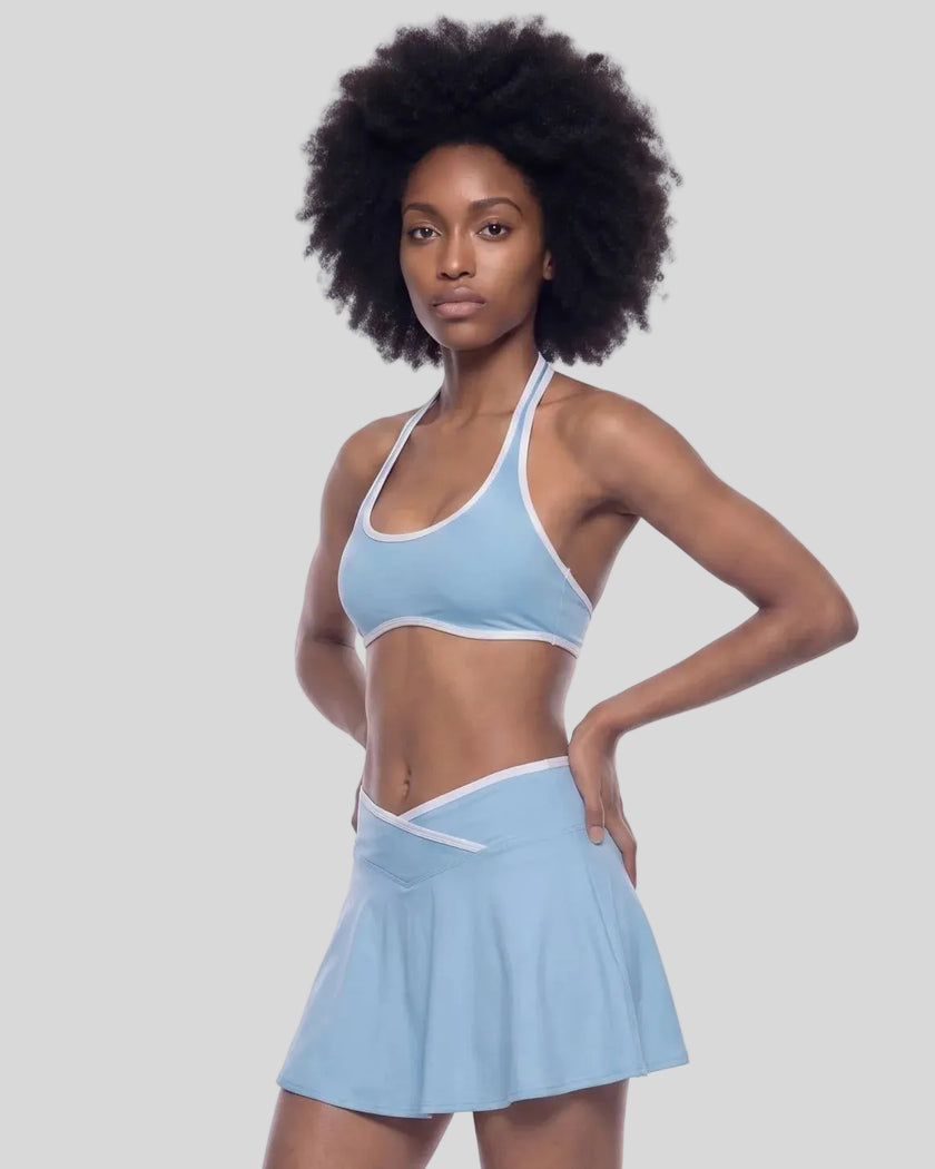 Three-quarter left view of a model wearing the CourtClub Color Block Halter Sports Bra in Sky Blue