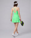Woman wearing CourtClub Crossback Dress in Green, mid-body angled back view highlighting the crisscross straps and open keyhole detail