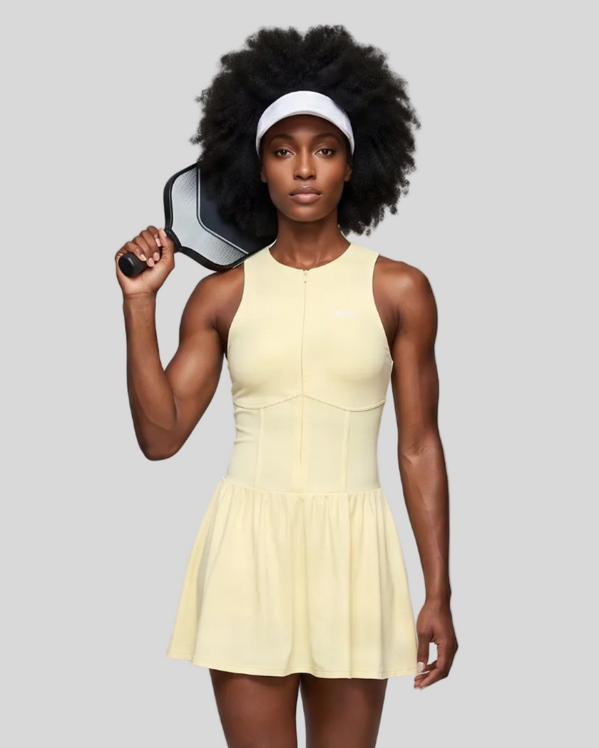Woman wearing the Athlesi CourtClub Full-Zip Dress in Light Yellow, closer front view highlighting the neckline, zipper and fitted bodice.