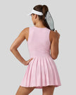 Woman wearing the Athlesi CourtClub Full-Zip Dress in Pink, closer back view highlighting the sleeveless fit and waistline.
