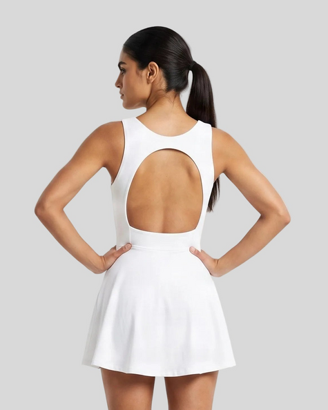 Woman wearing Athlesi CourtClub Open-Back Tennis Dress in White mid-body back view highlighting statement open-back detail