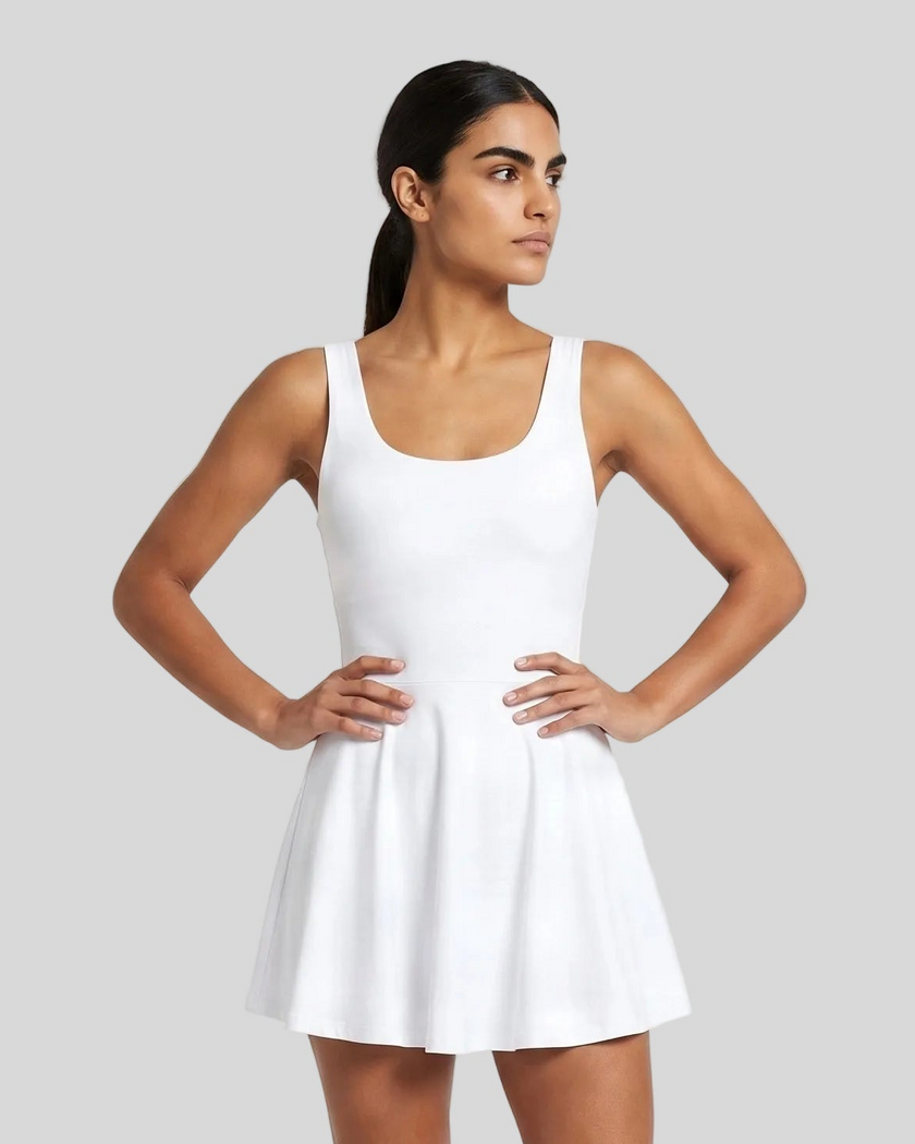 Woman wearing Athlesi CourtClub Open-Back Tennis Dress in White mid-body front view showing scoop neckline and flared silhouette