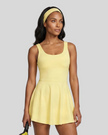 Woman wearing Athlesi CourtClub Open-Back Tennis Dress in Yellow mid-body front view showing scoop neckline and flared silhouette