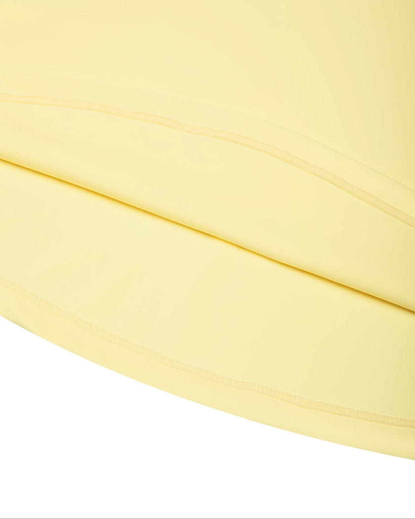 Athlesi CourtClub Open-Back Tennis Dress in Yellow closeup of flared skirt and finished hem