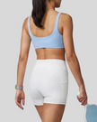 Woman wearing Athlesi CourtClub Tennis Short in White mid-body back view highlighting sculpted waistband seam and fit