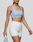 Woman wearing Athlesi CourtClub Tennis Short in White mid-body front view highlighting waistband and fitted silhouette