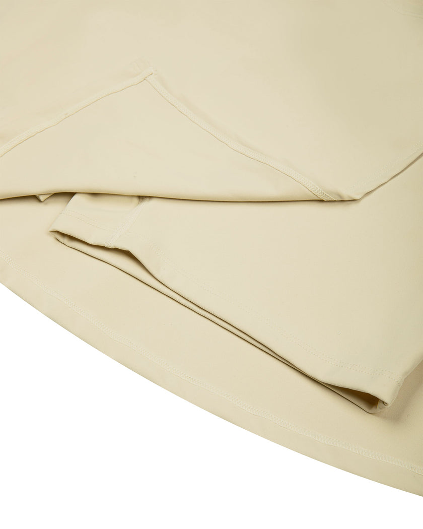 Close-up of the skirt and built-in shorts construction on the Athlesi CourtClub Tie-Front Dress in Light Apricot.