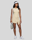 Woman wearing the Athlesi CourtClub Tie-Front Dress in Light Apricot, full-body front view.