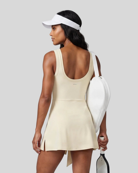 Woman wearing the Athlesi CourtClub Tie-Front Dress in Light Apricot, mid-body back view highlighting the scoop neckline and fit.