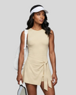 Woman wearing the Athlesi CourtClub Tie-Front Dress in Light Apricot, mid-body front view highlighting the asymmetric tie detail.