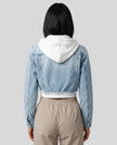 Back view of model wearing Athlesi EdgeForm light blue denim jacket over a white crop top and beige pants