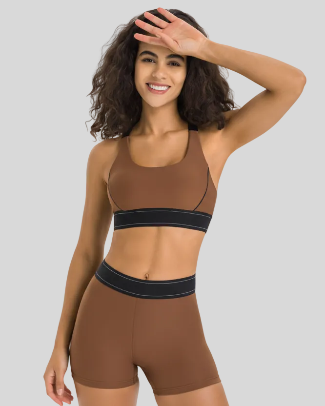 Woman wearing a brown sports bra and shorts set on a gray background