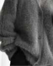 Close up of dark gray cardigan worn by a person on a white background