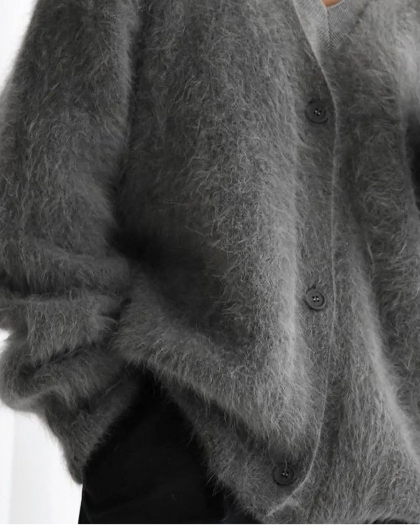 Close up of dark gray cardigan worn by a person on a white background