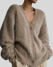 Close-up of a person wearing a fluffy khaki cardigan against a gray background