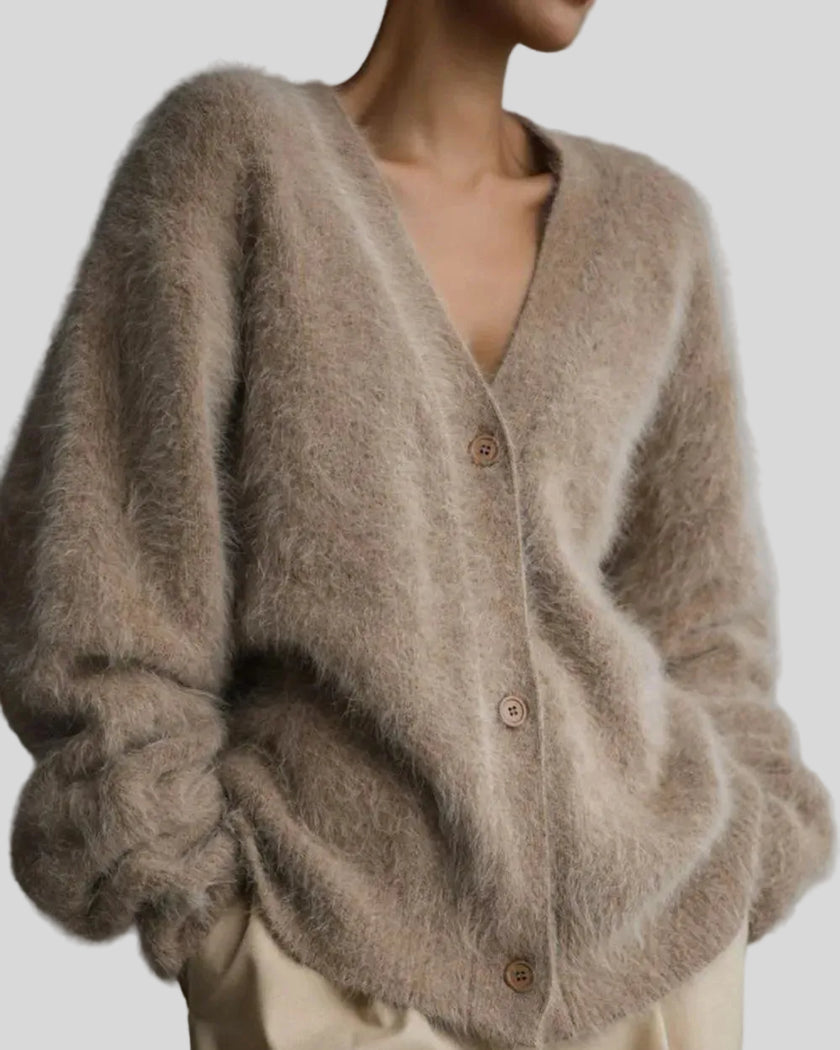 Close-up of a person wearing a fluffy khaki cardigan against a gray background