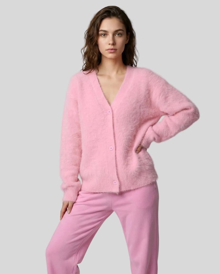 Woman wearing a pink cardigan and pants on a light gray background