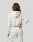 Back view of a model wearing the Everyday Cropped Zip-Up Hoodie in Oat Gray
