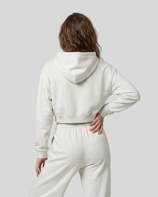 Back view of a model wearing the Everyday Cropped Zip-Up Hoodie in Oat Gray
