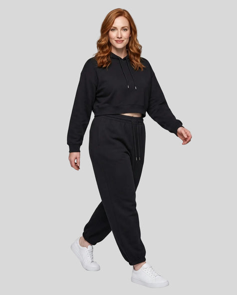 A woman modeling a black Everyday Cropped Hoodie and matching Everyday Jogger Pants set with white sneakers.