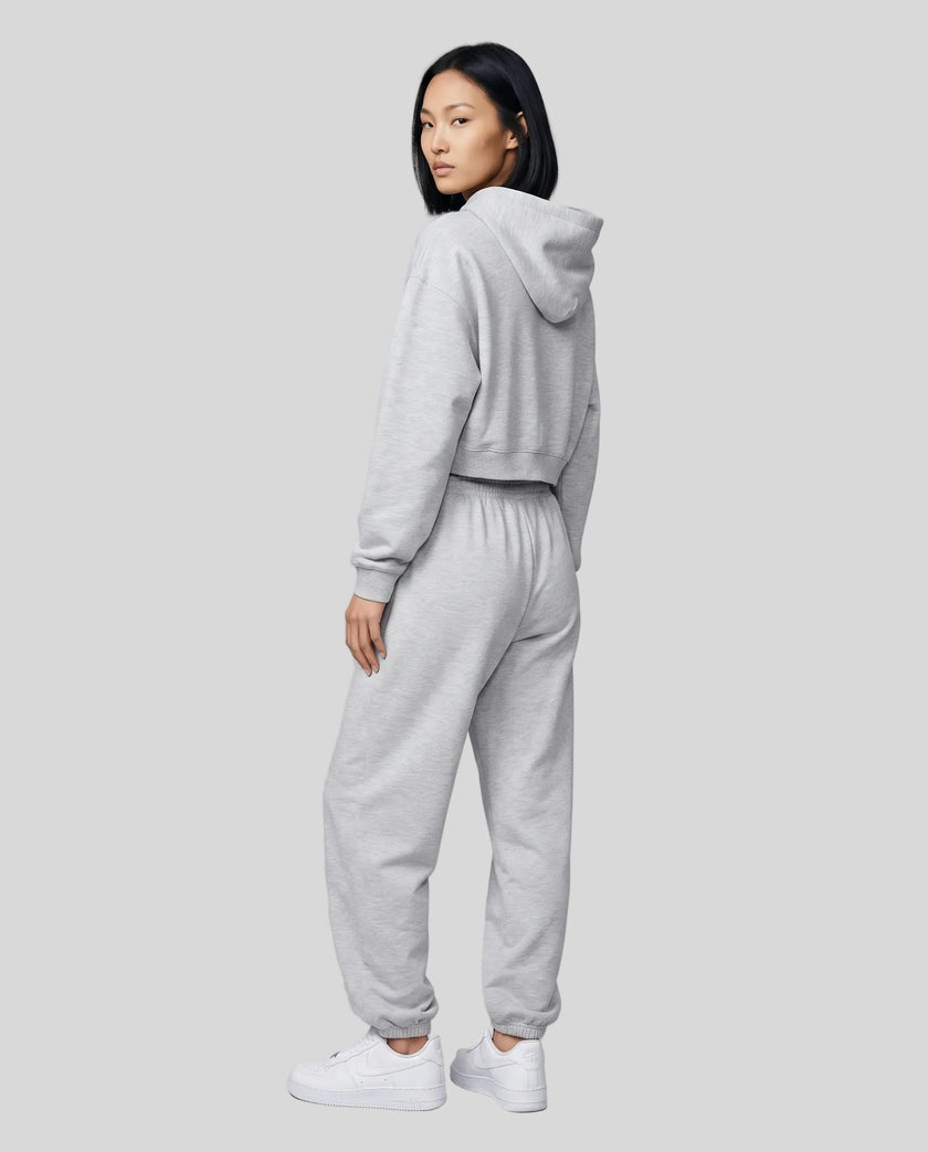 A model viewed from the back wearing a matching flower gray Everyday Cropped Hoodie and Everyday Jogger Pants set, paired with white sneakers.