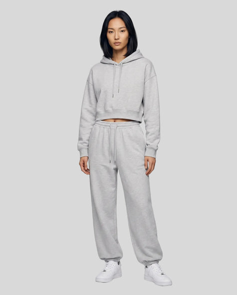 A woman modeling a flower gray Everyday Cropped Hoodie and matching Everyday Jogger Pants set with white sneakers.
