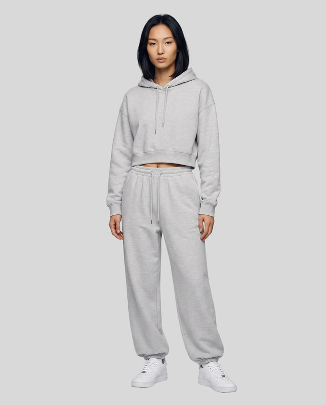 A woman modeling a flower gray Everyday Cropped Hoodie and matching Everyday Jogger Pants set with white sneakers.