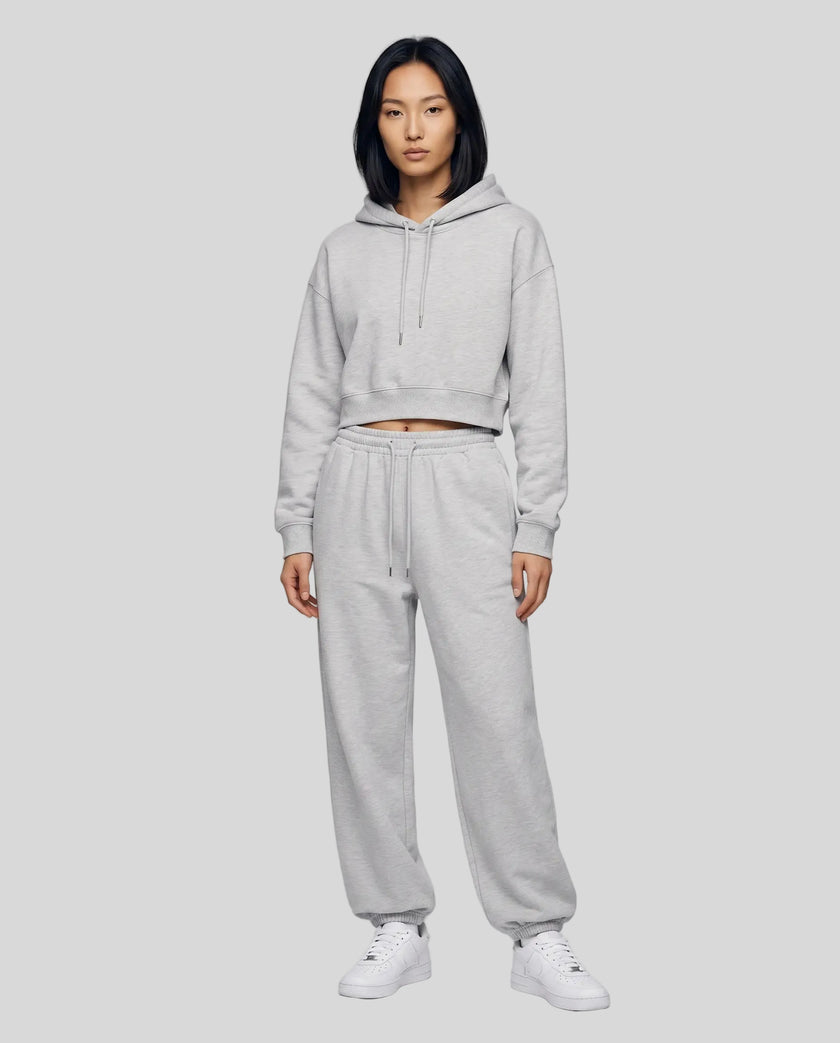 A woman modeling a flower gray Everyday Cropped Hoodie and matching Everyday Jogger Pants set with white sneakers.