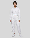 A woman modeling a white Everyday Cropped Hoodie and matching Everyday Jogger Pants set with white sneakers.