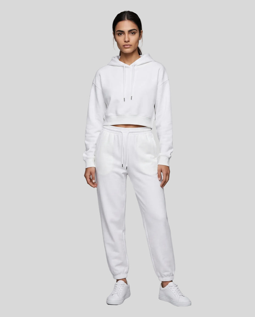 A woman modeling a white Everyday Cropped Hoodie and matching Everyday Jogger Pants set with white sneakers.
