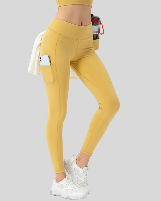 Gold flowform utility leggings worn by a woman on a gray background