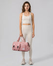 Model holding a burnt coral FlowHold Carry Bag in front with both hands styled for everyday movement