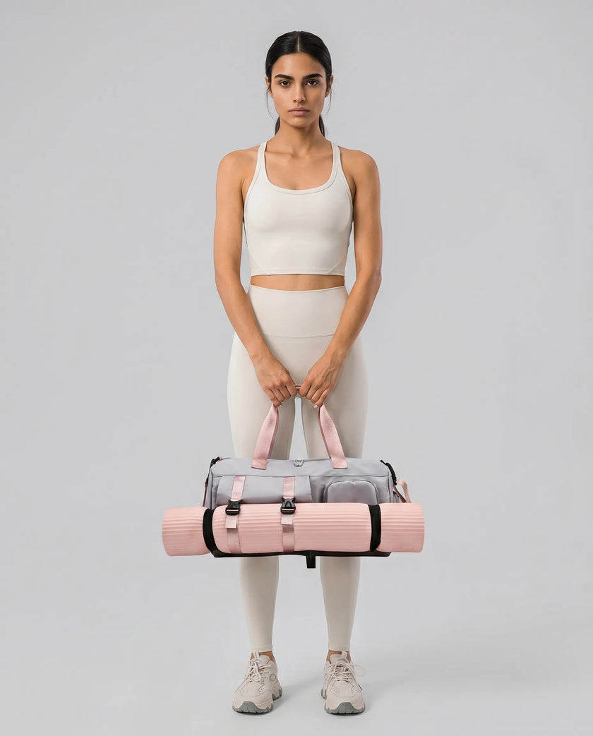 Woman holding a pink and gray Flow Hold Carry Bag with a yoga mat inside on a neutral studio setting