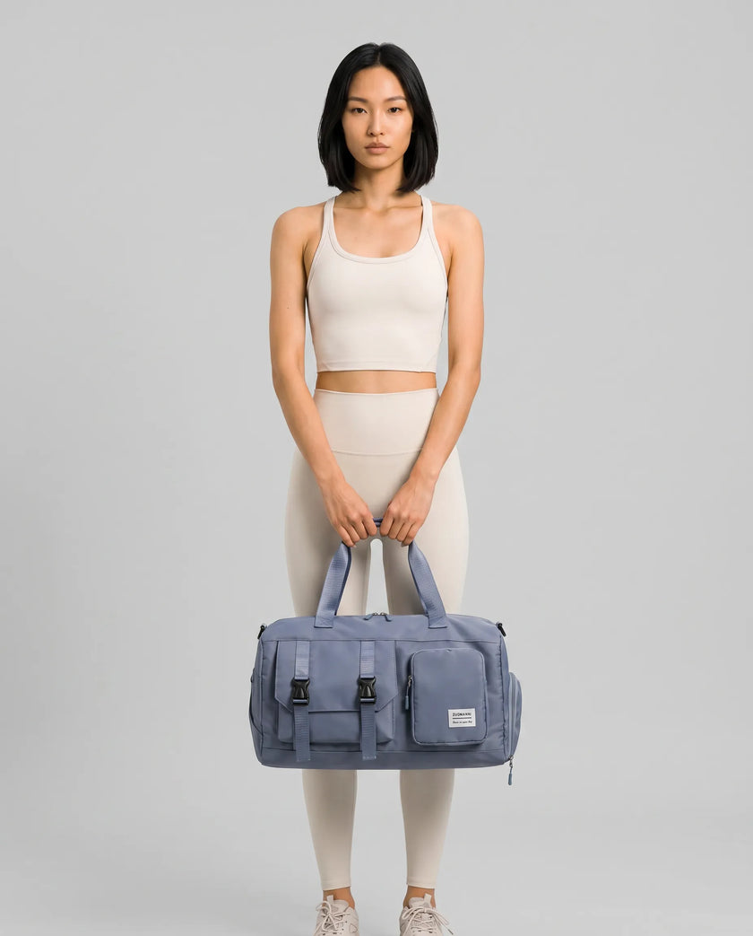 Model holding a light indigo FlowHold Carry Bag in front with both hands styled for everyday movement