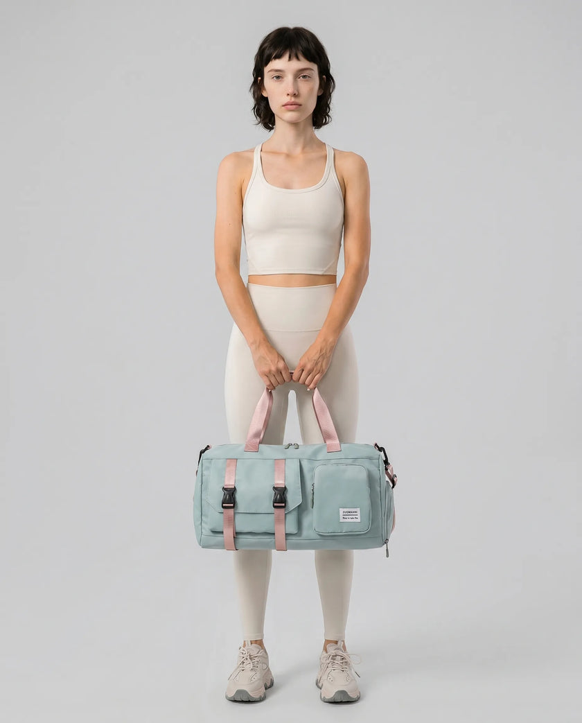 Model holding a turquoise FlowHold Carry Bag in front with both hands styled for everyday movement
