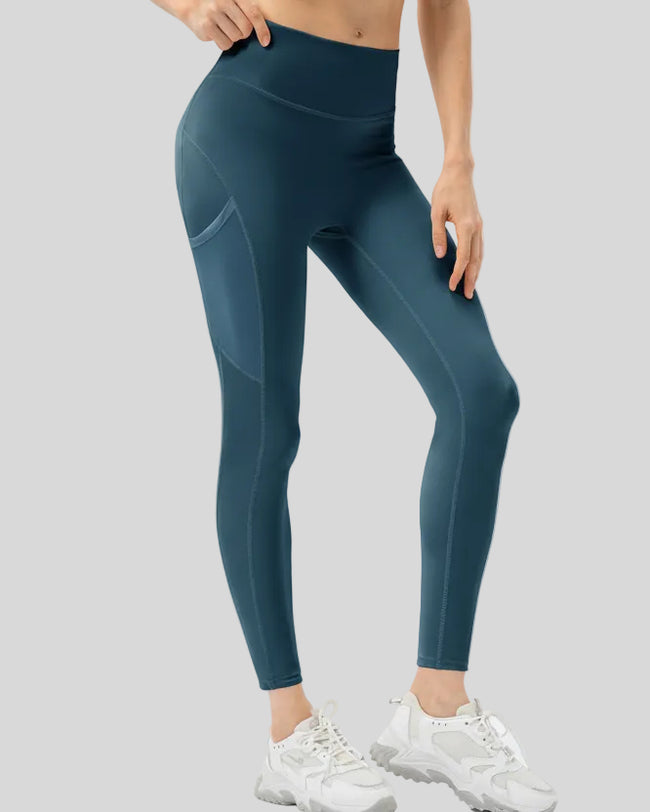 Front view of Athlesi FlowMotion Trail Pocket Legging in deep teal with visible seam detailing