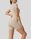 Back view of FlowZip short-sleeve romper in tan with clean, fitted silhouette