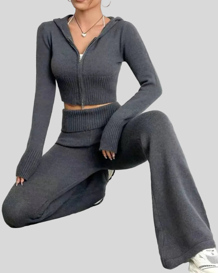 Model crouching wearing dark gray Athlesi FormFlare zip hoodie and flare pant set showing stretch and fit
