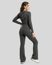 Model back full body wearing dark gray Athlesi FormFlare zip hoodie and flare pant set