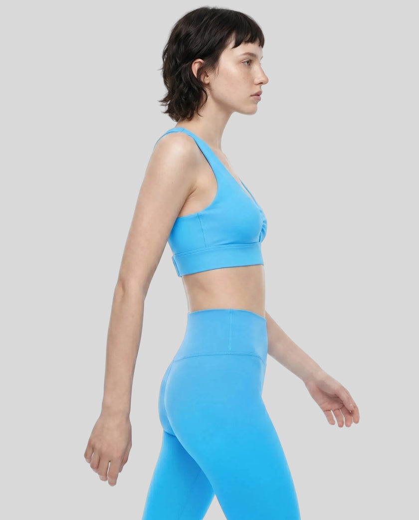 Angled side view of the FormLine Twist Sports Bra paired with activewear bottoms