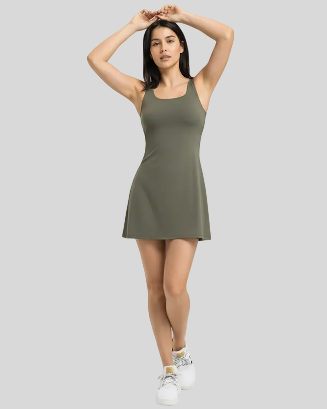 Woman wearing a green activewear dress on a gray background