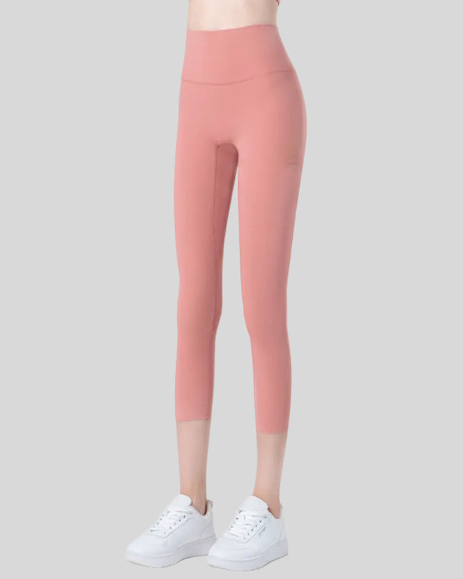 Angled front view of Athlesi GlowForm Sculpt Cropped Legging in coral