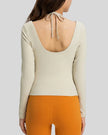 Back view showing open-back halter design with adjustable tie on Athlesi HaloContour top in ivory