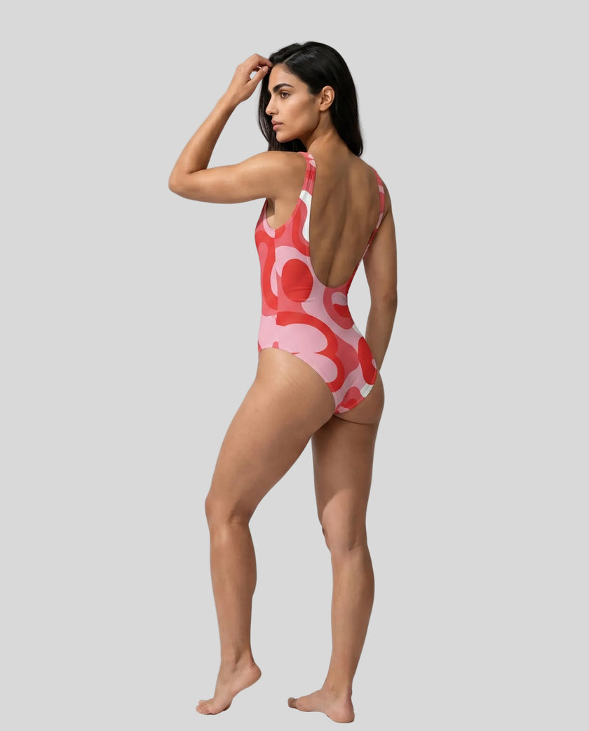 Model wearing red swirl swimsuit back left angle view