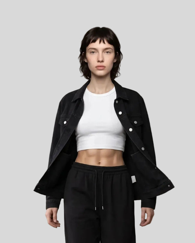 A model walks forward wearing a Heritage Denim Jacket in Black over a White tank top, Black Everyday Jogger Pants, and white sneakers.