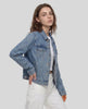 A woman modeling a blue Heritage Denim Jacket over a White tank top, paired with White wide-leg jeans and white sneakers.