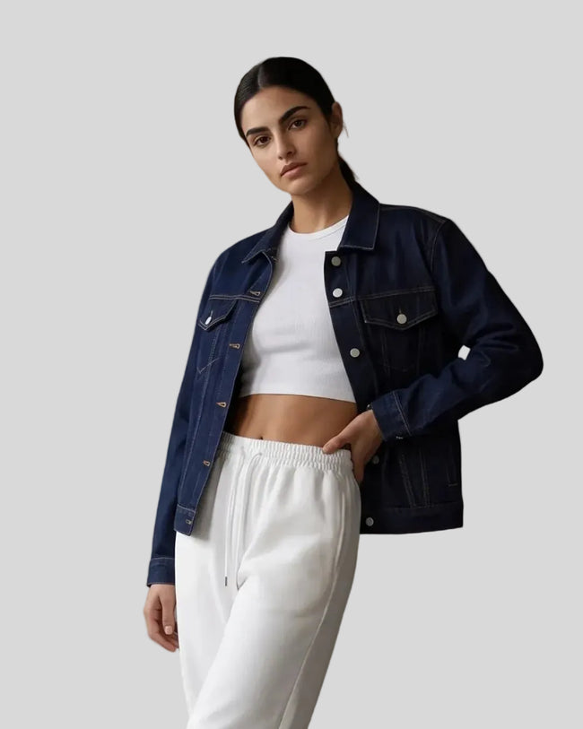 A woman modeling a Navy Blue Heritage Denim Jacket over a White tank top and White Everyday Jogger Pants, paired with white sneakers.