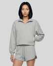 A model wearing a flower gray Athlesi Heritage Quarter-Zip Sweatshirt and matching shorts, paired with white sneakers.
