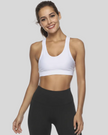Woman wearing a white sports bra and black leggings on a plain background